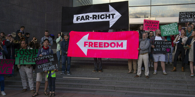 Demonstranten halten zwei Banner in die Luft: "Far Right" und "Freedom", mit Pfeilen in entgegengesetzter Richtung.