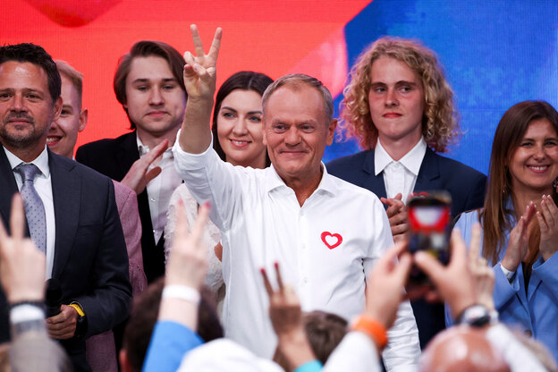 Donald Tusk zeigt auf einer Bühne das Victory-Zeichen, im Hintergrund vor allem jüngere Leute