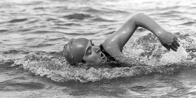 Schwarz-weiß-Foto: Ein Mann mit Badekappe schwimmt im Kraul