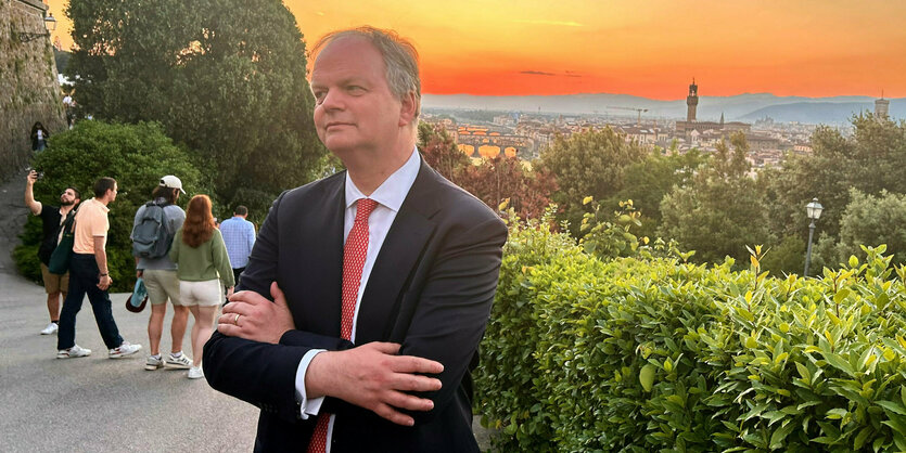 Eike Schmidt verschränkt die Arme vor Sonneuntergang und Florenzpanorama