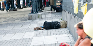 Menschen schlafen und sitzen vor dem Hamburger Hauptbahnhof.