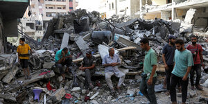 Palästinenser laufen zwischen Trümmern
