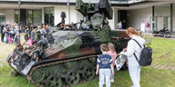Eine Mutter mit zwei Kinder steht vor einem Luftlandepanzer der Bundeswehr.