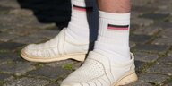 Eine Person trägt Socken mit Deutschlandflagge und Gesundheitsschuhe.