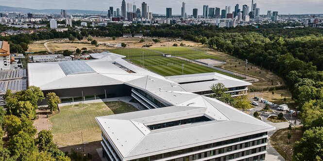 Luftaufnahme eines großen Gebäudes, im Hintergrund die Skyline von Frankfurt