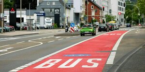 Busspur auf der Straße in einer kleinen Stadt, die Bussspur ist breit, rot und darauf steht mit weisser Schrift: BUS