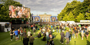 Menschen auf der mit Kunstrasen ausgelegten Fanmeile vor dem Brandenburger Tor