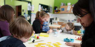 Padagoginnen mit Kita-Kindern an einem Tisch