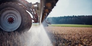 Trecker fährt über ein Feld und sprüht.