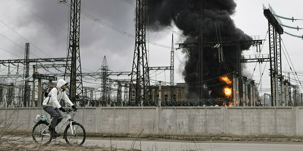 Charkiw: Ein Mann radelt nach einem russischen Angriff an einem brennenden Elektrizitätswerk vorbei.
