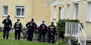 Polizeibeamte stehen nebeneinander vor einem Wohnblock