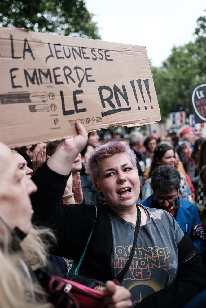 Eine Frau steht in einer menschenmenge und hält ein Schild in den Händen