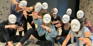 Jugendliche mit Masken bei einem Theaterstück.