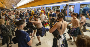 Schottische Fans in Röcken und mit Dudelsack tanzen an einem U-Bahnhof