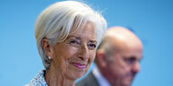 Christine Lagarde lächelt während einer Pressekonferenz vor blauem Hintergrund