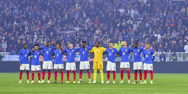 Das französische Nationalteam steht Arm in Arm im Stadion, darunter Marcus Thuram