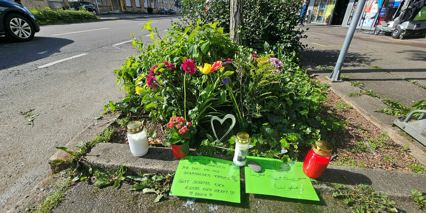 Blumen, Kerzen und Karten an einem Baum auf einem Bürgersteig