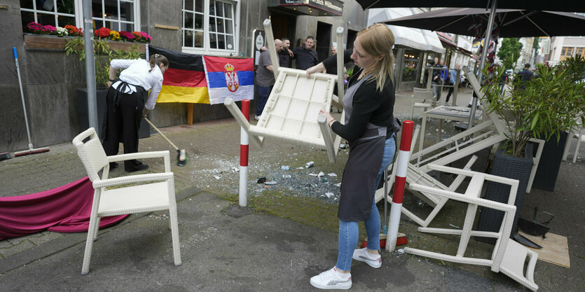 Eine Frau räumt die verwüstete Freischankfläche vor einem Lokal auf