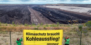 Greenpeace-Aktivistinnen mit Banner vor Braunkohle