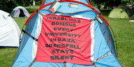 Blaues Zelt mit Protestplakat und Palästinaflaggen