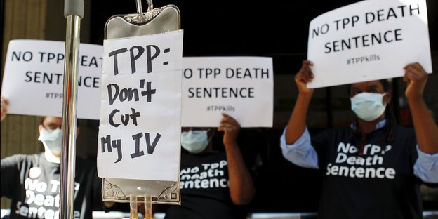 Demonstranten protestieren mit Schildern gegen das Freihandelsabkommen TPP.