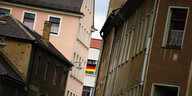 Eine Deutschland-Fahne hängt vor einem Fenster mitten in einer engen Häusergasse in Kamenz.
