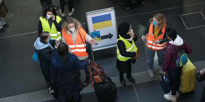 Eine ukrainische Flagge und Menschen in einer Halle.