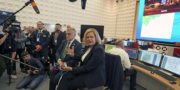 Ein Raum mit vielen Bildschirmen und zwei deutschen Innenministern