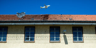 Ein Flugzeug fliegt im Himmel über einem Gefängnis