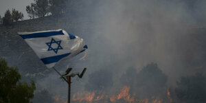 Eine israelische Flagge vor einer brennenden Landschaft