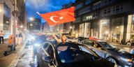 Eine schwarze Limousine aus der eine große türkische Fahne geschwenkt wird