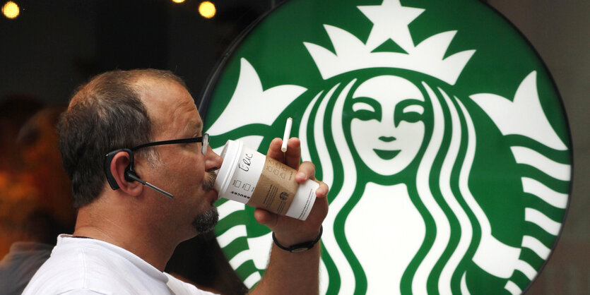 Ein Mann geht mit einem To-go-Becher an einer Starbucks-Filiale in Seattle vorbei.