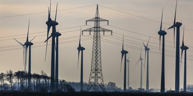 Silhouetten von Windrädern und einem Strommasten