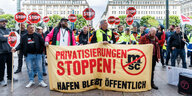 Hafenarbeiter demonstrieren mit einem Banner "Privatisierung stoppen"