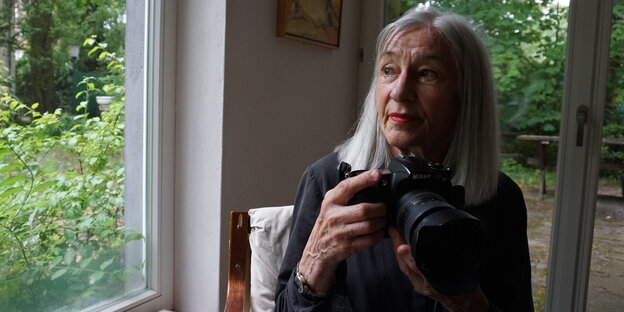 Renate von Mangoldt sitzt mit der Kamera in den Händen am Fenster