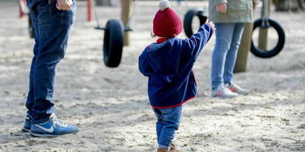 Ein Kind steht mit seinen Eltern auf einem Spielplatz im Volkspark Wilmersdorf. Nachdem Spielplätze zur Eindämmung des Coronavirus geschlossen waren, öffnen diese nun wieder