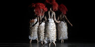VierTänzerinnen auf ihren Fußspitzen mit nacktem Oberkörper