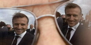 Präsident Macron wird in den Gläsern einer Sonnenbrille gespiegelt.