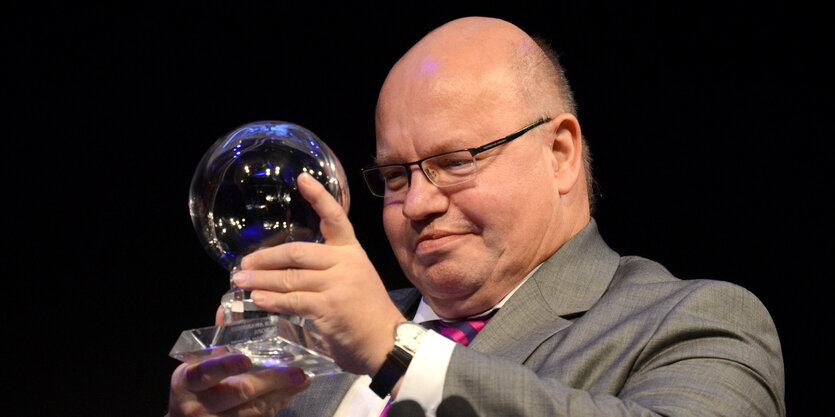 Peter Altmaier hält einen Glaspokal