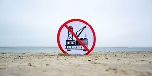 Schild mit durchgestrichener Erdgas-Bohranlage am Strand.