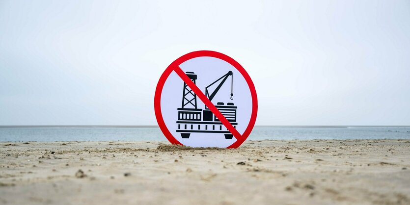 Schild mit durchgestrichener Erdgas-Bohranlage am Strand.