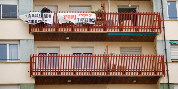 Protestbanner an einem Balkon, auf einem Balkon steht ein Mann.