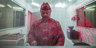 Ein Mann in chinesischem Gewand steht in einer Küche und schneidet etwas