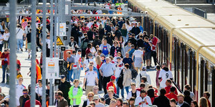 Hunderte von Fußballfans stehen auf einem Gleis vor einer Berliner S-Bahn