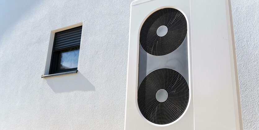 Wärmepumpe vor einer Hauswand, daneben kleines Fenster