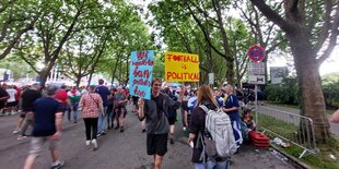 Demonstrant mit Pappschildern auf einem bevölkerten Weg, der zum Stadion führt