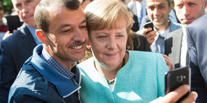 Ein geflohener Mann und Merkel machen ein Selfie