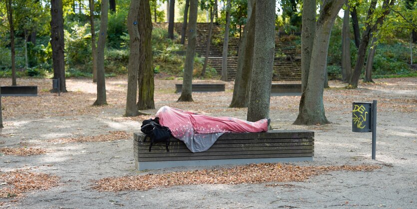 Eine obdachlose Person schläft auf einer Bank