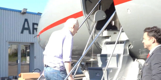 Julian Assange steigt in ein Flugzeug ein.