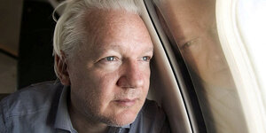 Assange blickt durch ein Flugzeugfenster